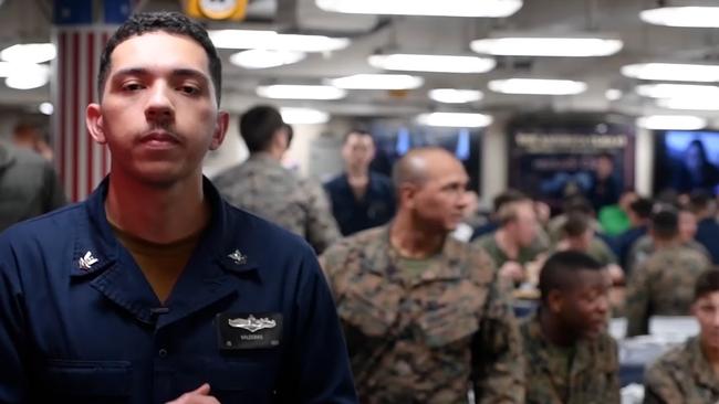 Information Specialist Second Class Andrew Valderas stands in front of US Marines and sailors as he talks about the USS America in an exclusive video made for the Courier Mail in this still from a video. Picture: Supplied