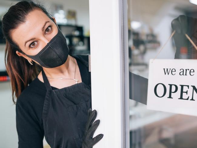 Commercial editorial. Happy business owner hanging an open sign during COVID-19. Picture: iStock