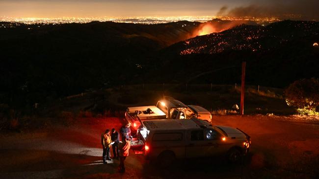 The downtown Los Angeles skyline (far L) is seen in the distance as firefighters monitor the Palisades fire near the Mandeville Canyon neighborhood and Encino, California. Picture: Patrick T. Fallon / AFP