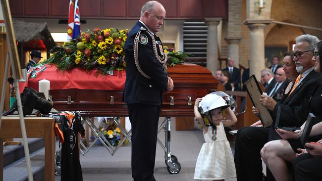 Charlotte O'Dwyer, the young daughter of Rural Fire Service volunteer Andrew O'Dwyer, wears her fathers helmet during the funeral on January 7, 2020. Photo: Dean Lewins-Pool