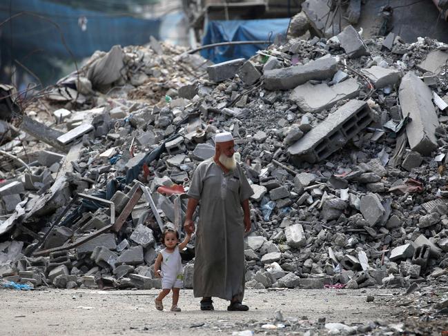 An elderly man holds a child by the hand as he walks past a building levelled by Israeli bombardment in the Bureij refugee camp in central Gaza Strip. Picture: AFP