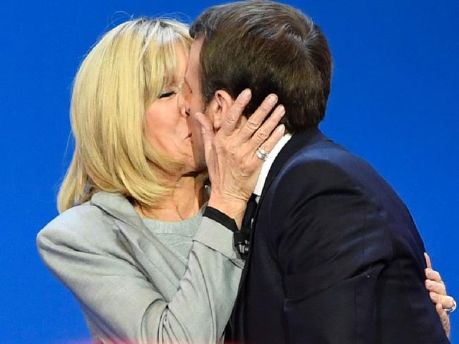 (FILES) This file photo taken on April 23, 2017 shows French presidential election candidate for the En Marche ! movement Emmanuel Macron kissing his wife Brigitte Trogneux (L) on stage at the Parc des Expositions in Paris, after the first round of the Presidential election. Emmanuel Macron was elected French president on May 7, 2017 in a resounding victory over far-right rival Marine Le Pen after a deeply divisive campaign, initial estimates showed. Brigitte Trogneux has been in her husband's life since he was 15 -- first as a teacher, then lover and now as his first lady. And she will be at Emmanuel Macron's side when the 39-year-old pro-EU centrist takes office as modern France's youngest ever president, after winning Sunday's decisive run-off vote.  / AFP PHOTO / Eric FEFERBERG / ALTERNATIVE CROP