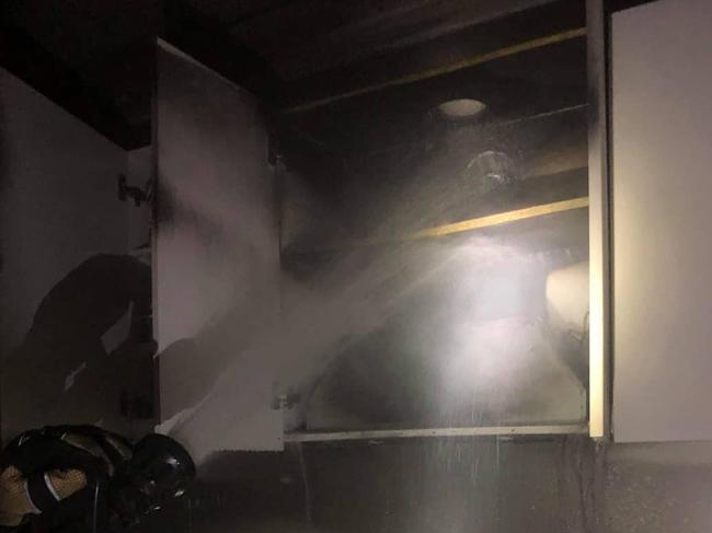 A Fire and Rescue NSW firefighter from the Forestville brigade puts out a fire in the kitchen of a home in Hurdis Ave, Frenchs Forest, that started in the rangehood. Picture: Fire and Rescue (Forestville)