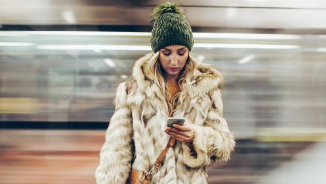 Depressed young girl uisng her phone while waiting for her traing on the subway