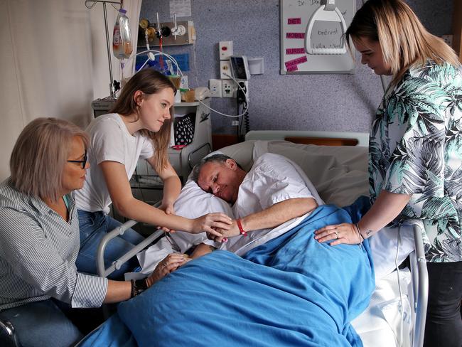 Mr Mitchell, who now requires 24hr care, surrounded by his wife Colleen and daughters Bailey and Morgan. Picture: Sam Ruttyn