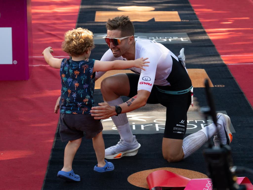 Matt Burton of Australia is met by his son at the finish line of the Cairns Airport IRONMAN Cairns. Picture Emily Barker.