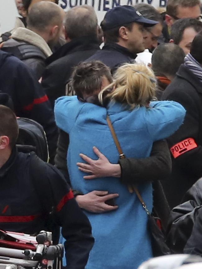 People hug each other outside Charlie Hebdo's office. Picture: Remy de la Mauviniere