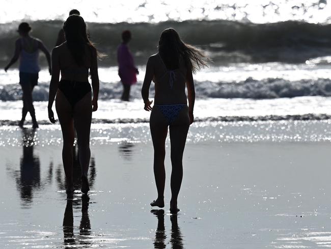 Foreign tourists walk on a beach in Seminyak, Badung regency on Indonesia resort island of Bali, on December 7, 2022. (Photo by SONNY TUMBELAKA / AFP)