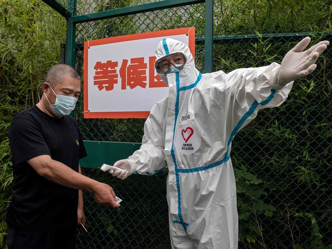 A man wearing a face mask gets his body temperature checked at the Xinjiekou urban forest in Beijing.