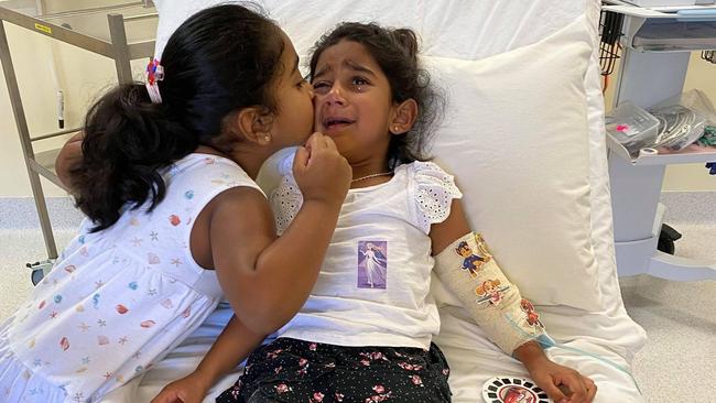 Tharnicaa, the youngest daughter of the ‘Biloela family’, is comforted by her sister Kopica after being hospitalised with a suspected blood infection. Picture: Supplied