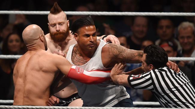 Former Germany goalkeeper Tim Wiese (2nd R) is held back by the WWE referee.