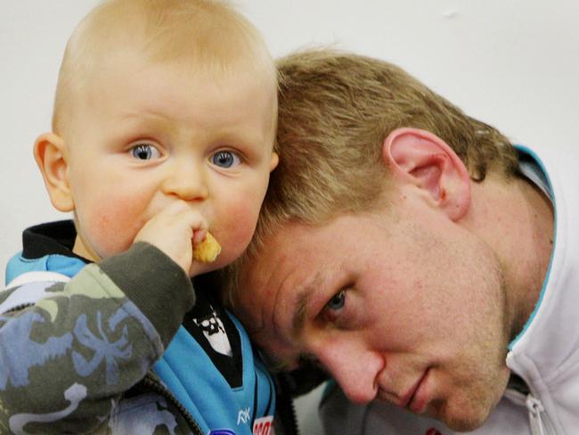 Kane has a moment with baby son Eddy after the 2007 Grand Final.