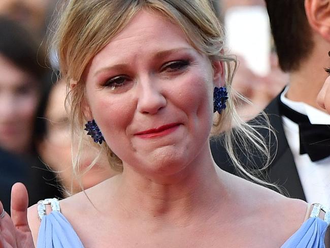 US actress Kirsten Dunst (C) cries as she arrives on May 24, 2017 with US actress Elle Fanning (L) and US director Sofia Coppola for the screening of the film 'The Beguiled' at the 70th edition of the Cannes Film Festival in Cannes, southern France.  / AFP PHOTO / Alberto PIZZOLI