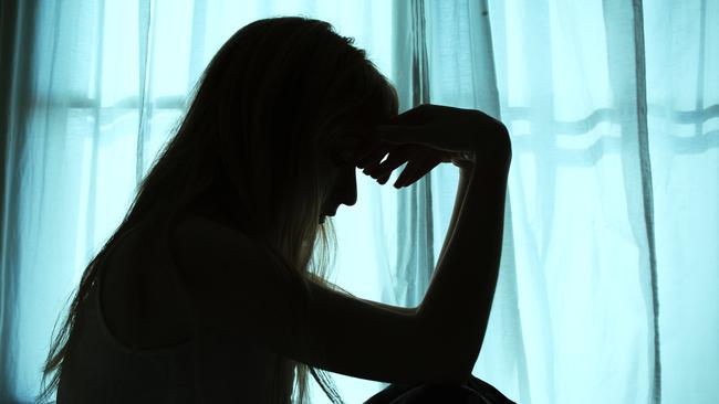 Silhouette of woman sitting in bed by window