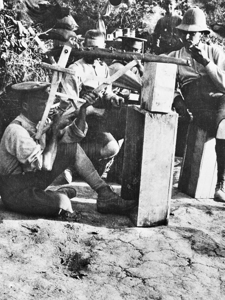 Private George Tostee (left), E Company, 10th Infantry Battalion, demonstrates a periscope rifle he had invented to the battalion CO, Lieutenant Colonel Stanley Price Weir (right, with pipe in mouth), and other battalion officers. Picture: Australian War Memorial