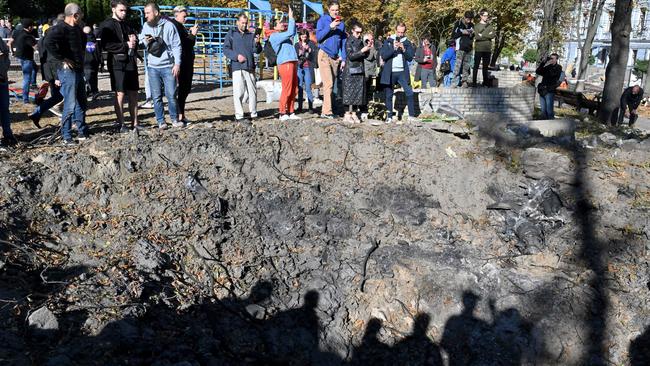 People stand by a rocket crater next to a child playground in central Kyiv on October 10. Picture: Sergei Supinsky / AFP