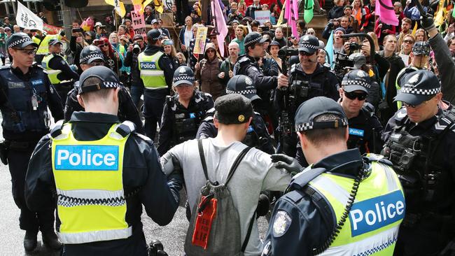 A protester is escorted away from the rally on Spring St. Picture: David Crosling