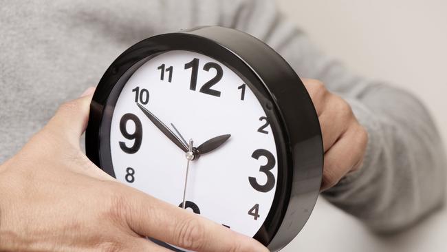 closeup of a young caucasian man adjusting the time of a clock