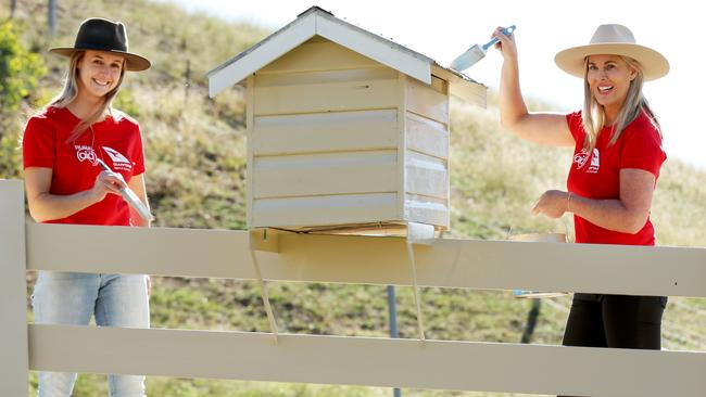 Qantas staff Nikki Stewart and Lauren Clarke paint the gate of Craig Murphy’s Murrurundi farm. Pictures: Jonathan Ng