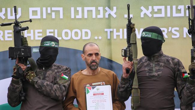 Hamas fighters escort Israeli hostage Eli Sharabi on a stage before handing him over to a Red Cross team in Deir el-Balah, central Gaza, on February 8, 2025. (Photo by Eyad BABA / AFP).