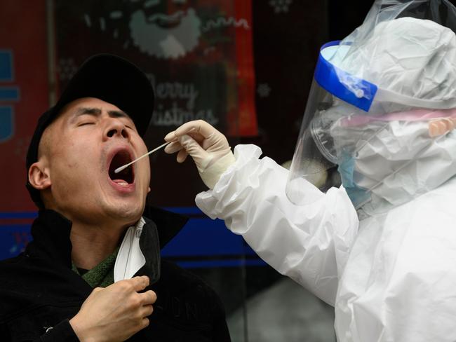 A medical worker wearing a hazmat suit gets a swab sample on a man to check if he has coronavirus. Picture: AFP