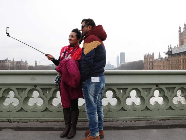 People take selfie photographs of themselves on Westminster Bridge in front of the Houses of Parliament in central London on March 23, 2017 after the bridge reopened to traffic following its closure during the March 22 terror attack. Picture: AFP
