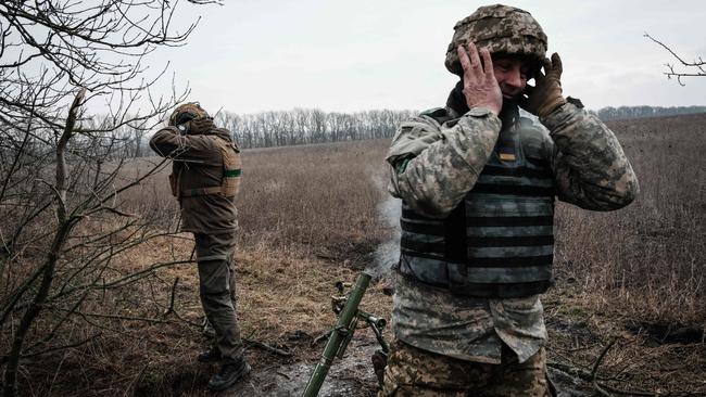 Ukrainian servicemen cover their ears as they fire a 60mm mortar toward Russian positions near the frontline in the Donetsk region on Wednesday (AEDT). Picture: AFP