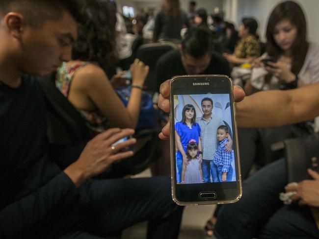 A relative shows a picture of passengers who were travelling on the missing AirAsia flight QZ8501 on her mobile phone screen at the airport in Surabaya, East Java.