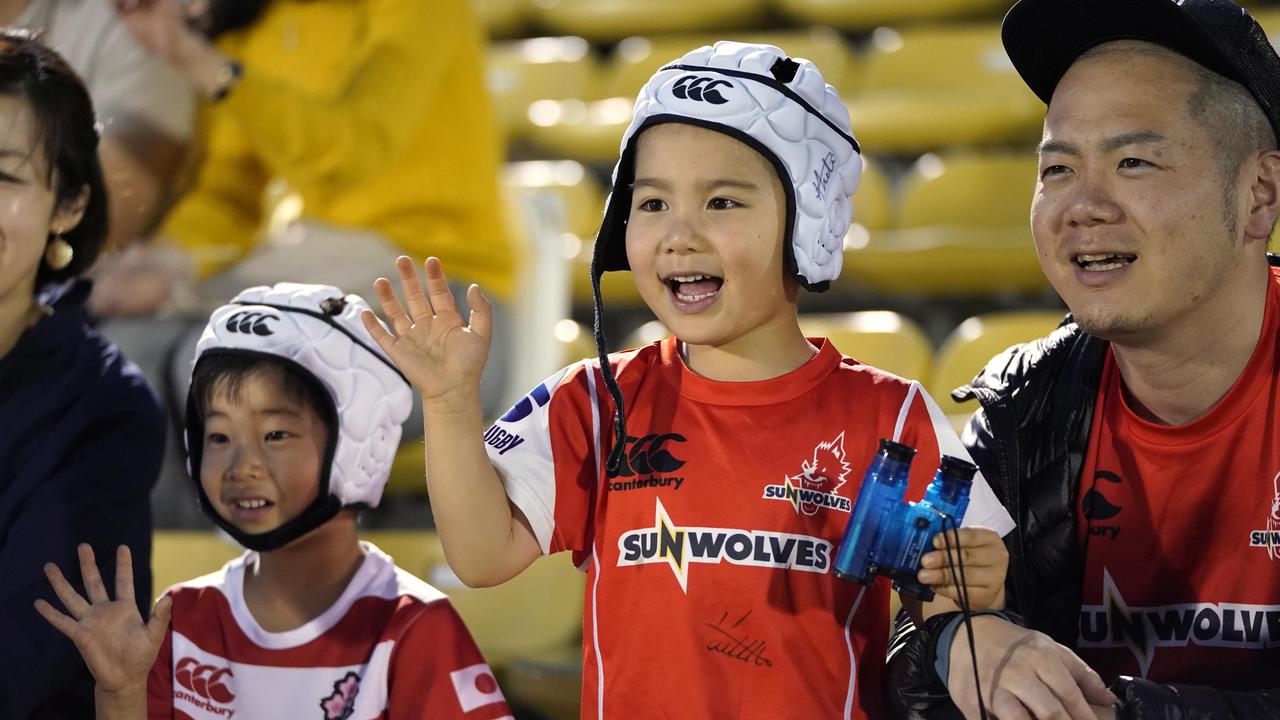 Young Sunwolves supporters wave to players prior to a Super Rugby match.