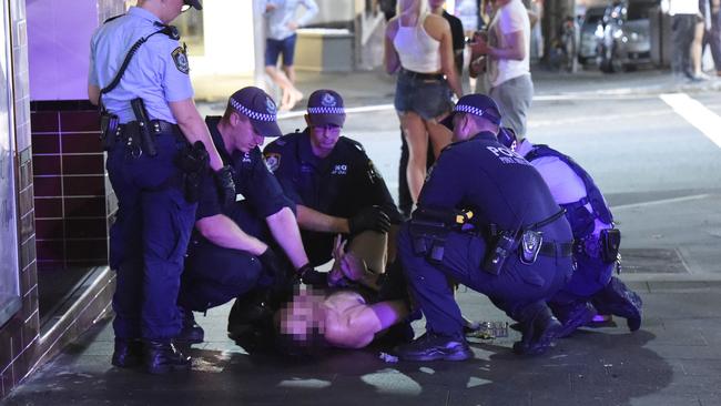 A man, believed to have taken ice, is held down by Sydney police officers as they wait for an ambulance crew to arrive and sedate him. Picture: Gordon McComiskie