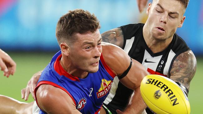 AFL Round 1. 19/03/2021. Collingwood vs Western Bulldogs at the MCG, Melbourne.   Bulldog Josh Dunkley clears by hand infant of Jamie Elliott of the Magpies during the 2nd qtr.     . Pic: Michael Klein