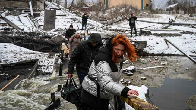 Civilians pick their way across a blown-up bridge on Kyiv’s northern front on Tuesday. Picture: AFP