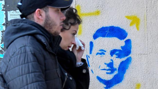 People walk past a stencil painting depicting Ukraine's President Volodymyr Zelensky on a building in downtown Podgorica. Picture: AFP