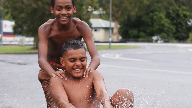 Cousins Sharma David, 12, and Levi Gorogo, 13, splash through puddles on their go kart on the road near their home, after heavy rain and wet weather in the Cairns region. Picture: Brendan Radke