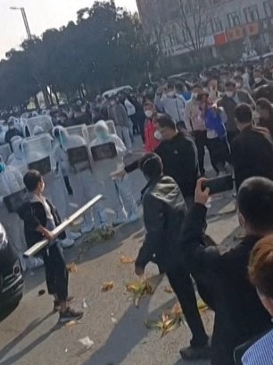 Workers at Foxconn’s iPhone factory clashed with riot police and people wearing hazmat suits. Picture: AFPTV/AFP Photo