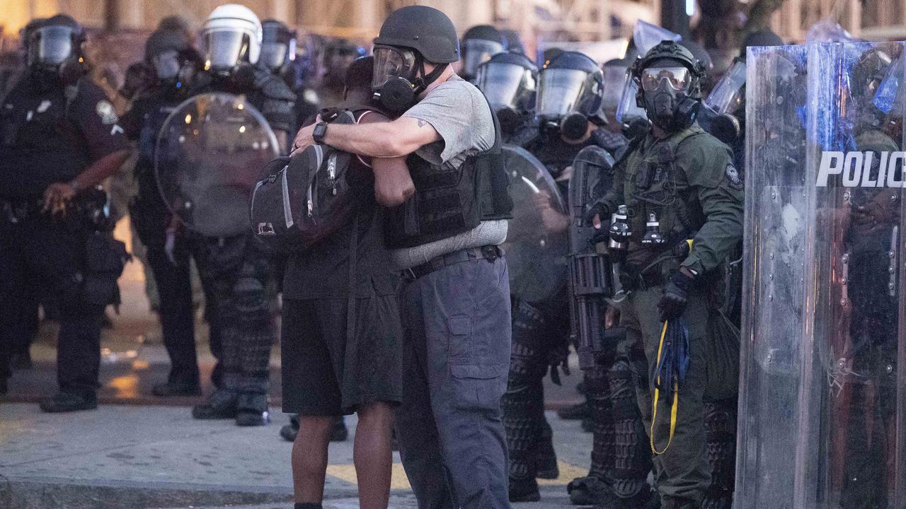 A police officer embraces a protester who helped disperse a crowd of people in Atlanta. Picture: John Bazemore/AP