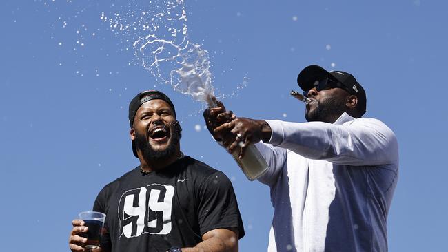 LOS ANGELES, CALIFORNIA - FEBRUARY 16: Aaron Donald #99 of the Los Angeles Rams (L) celebrates with champagne during the Super Bowl LVI Victory Parade on February 16, 2022 in Los Angeles, California.   Michael Owens/Getty Images/AFP == FOR NEWSPAPERS, INTERNET, TELCOS & TELEVISION USE ONLY ==