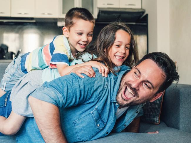 Young father playing with his two cute children on the sofa at home.