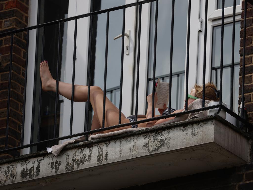 A woman sunbathes on a balcony in Hackney in London. Picture: Getty Images