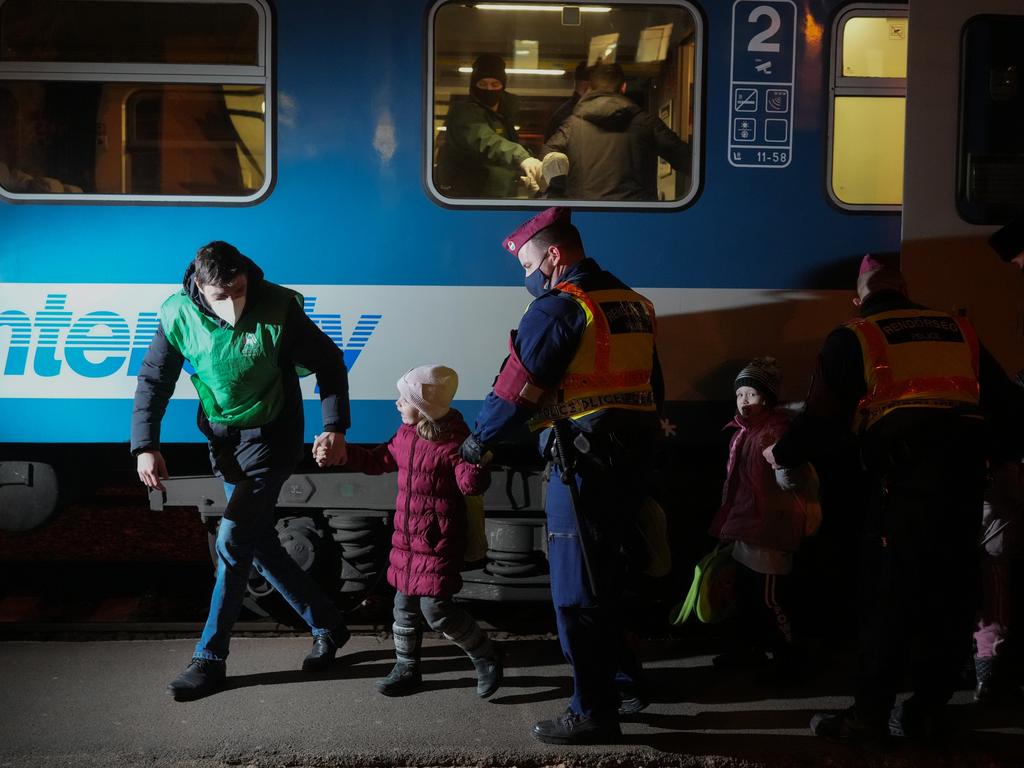 Hungarian police officers escort refugee children across the dark tracks at Zahony train station as the influx of refugees from Ukraine continues through the night. Picture: Getty Images