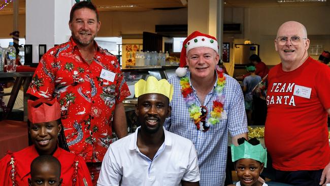 Cairns Community Christmas Lunch board member Paul Maguire, organiser David Lennie and board member Greg T Jones ensure that Alida Nduwimana, Kevin Bazungu, 7, Shukuru Bazungu and Leticia Bazungu have a traditional Christmas lunch of ham, turkey, roast vegetables and Christmas pudding with custard. Picture: Brendan Radke