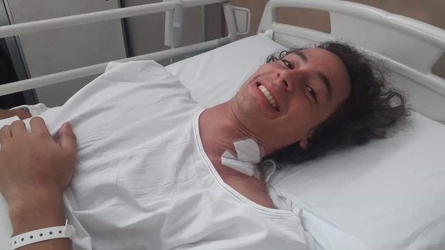 Grinning through the pain — Hobart motor racer Alex Peroni in San Gerardo hospital in Italy.