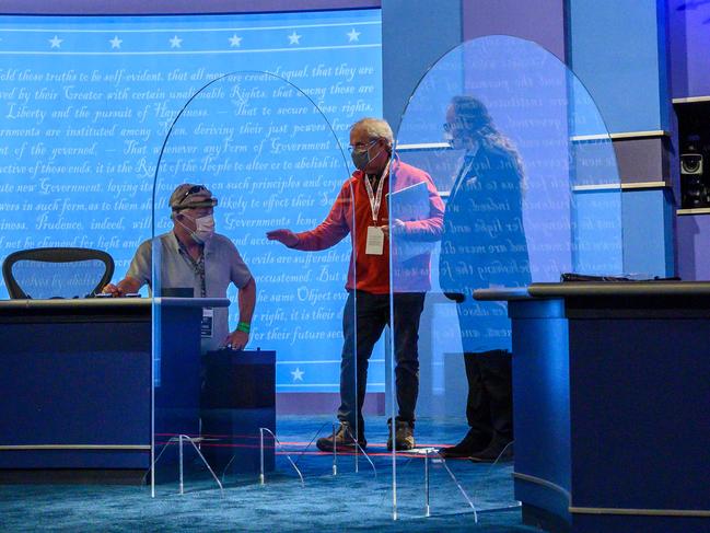 Workers inspect plexiglas protections erected between the debaters. Picture: AFP