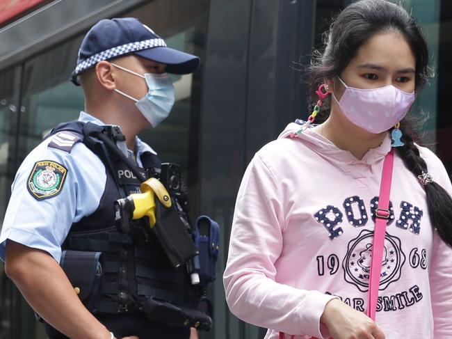 A mask wearing police officer waiting to board a tram in Martin Place.Picture: Christian Gilles