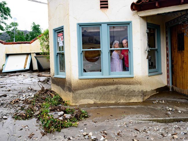 Residents trapped in their home peer out a window while waiting for help in Yucaipa, California. Picture: AFP