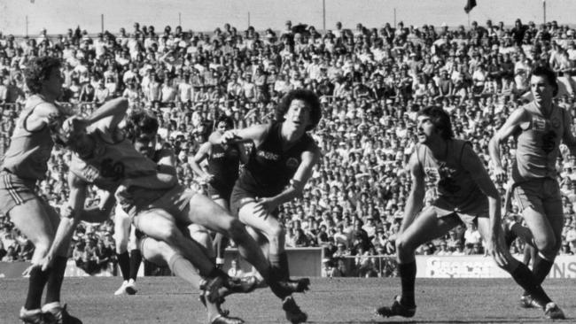 Sturt defender Colin Casey loses possession after being heavily tackled by Roger Woodcock.