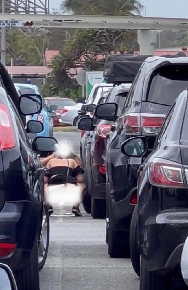 Photo of a girl urinating on the road while waiting in traffic to get to Spilt Milk.