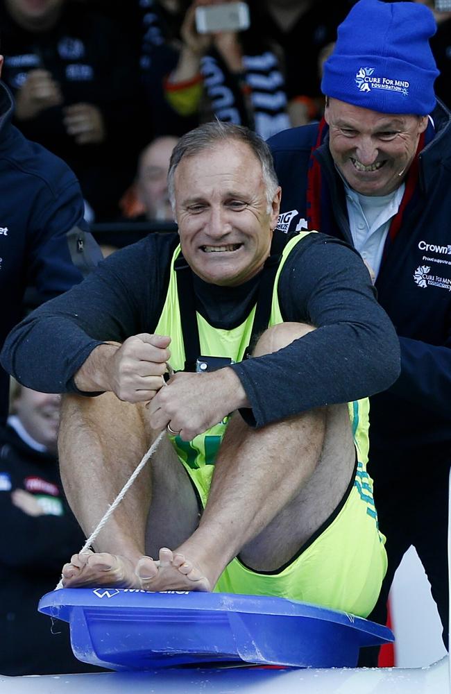 Tim Watson gets a push start from Neale Daniher as he heads down the slide towards the ice pool. Picture: Michael Klein