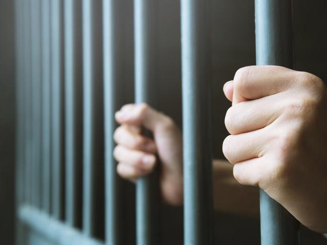 Man in prison hands of behind hold Steel cage jail bars. offender criminal locked in jail.