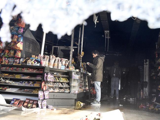 Staff inspect the fire damaged interior of a shop after an arson attack on Chapel Street. Picture: Andrew Henshaw